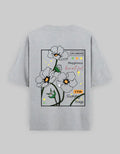 Gray oversized unisex t-shirt with graphic white flowers and text, streetwear style.